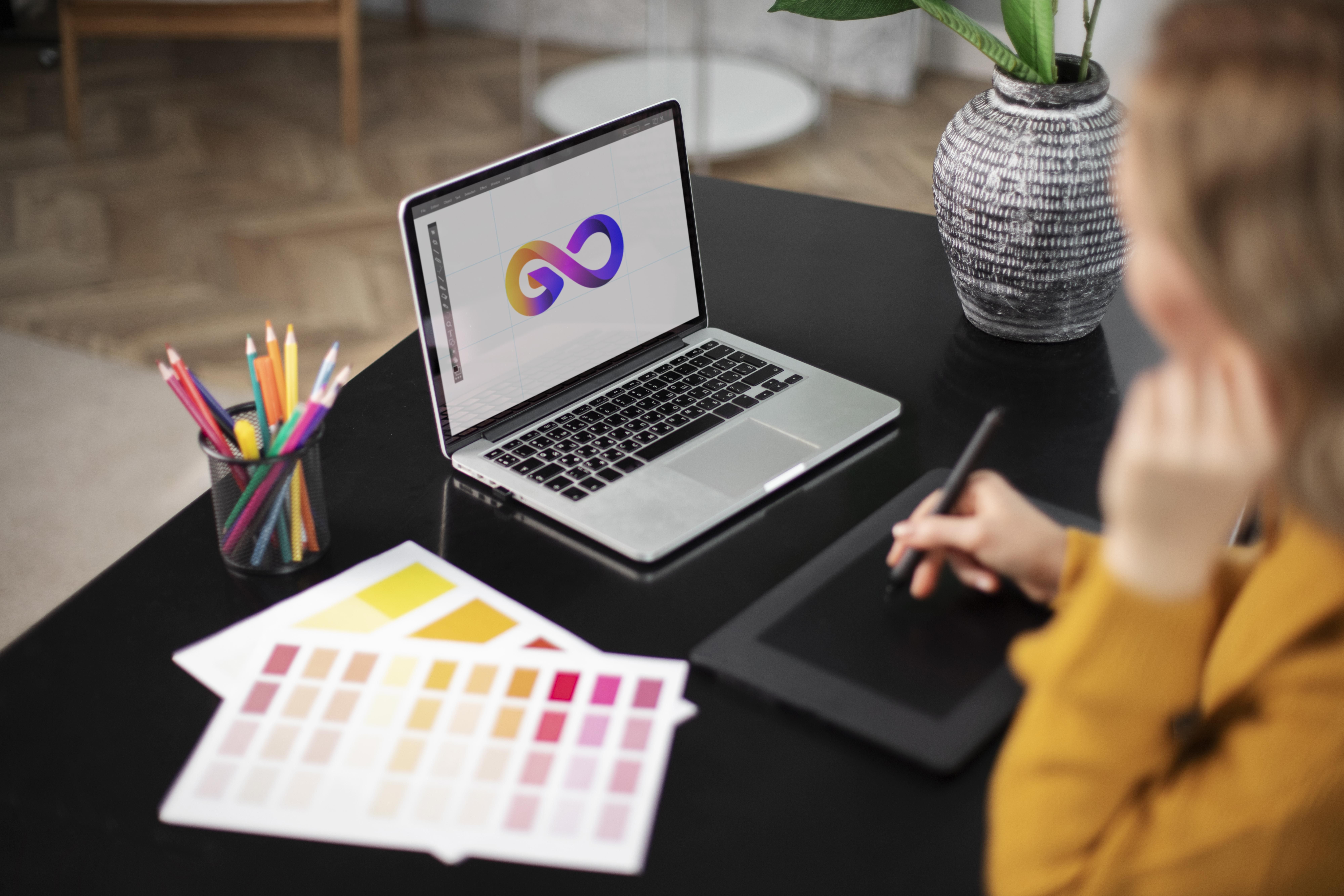 disenador-de-logotipo-femenino-trabajando-en-su-tableta-conectada-una-computadora-portatil